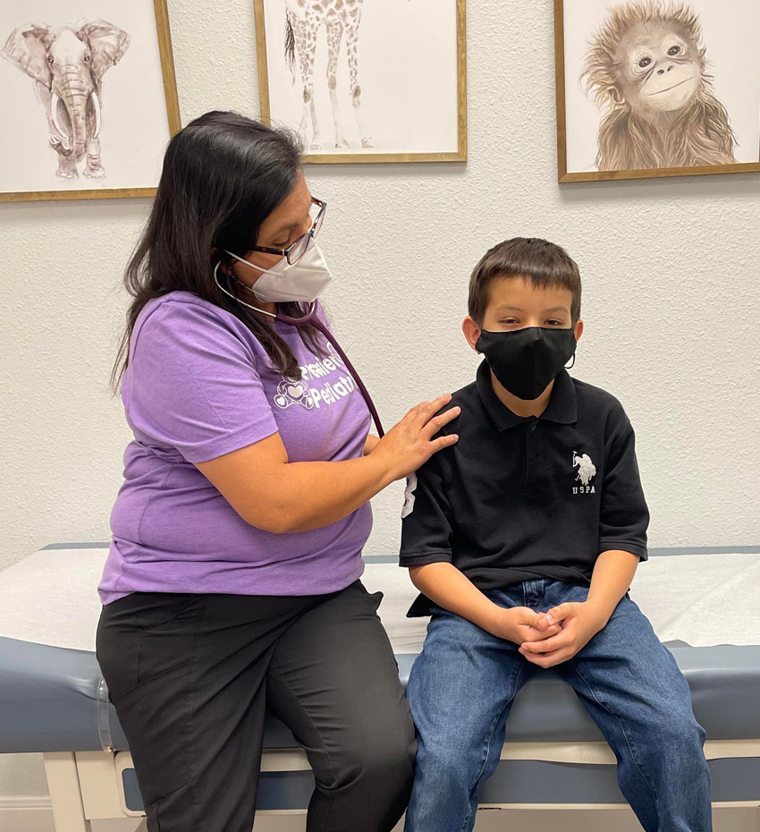 nurse practitioner examines a young boy in an exam room